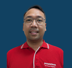A man in glasses wearing a red company shirt against a solid blue background.