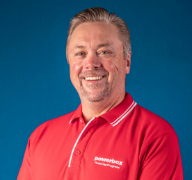 Smiling man in a red uniform posing against a blue background.