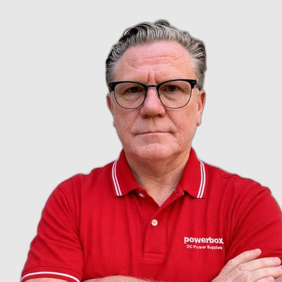 Man in red Powerbox polo shirt with arms crossed, wearing glasses, against plain background