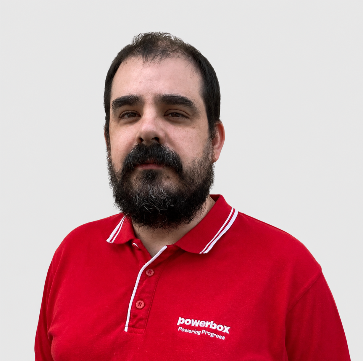 Man in red Powerbox polo shirt with 'Powering Progress' logo, representing industrial power solutions team