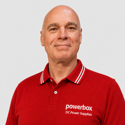 Man in red polo shirt with Powerbox DC Power Supplies logo, representing industrial power solutions
