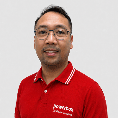 Man in red Powerbox polo shirt with DC Power Supplies text, smiling for professional headshot